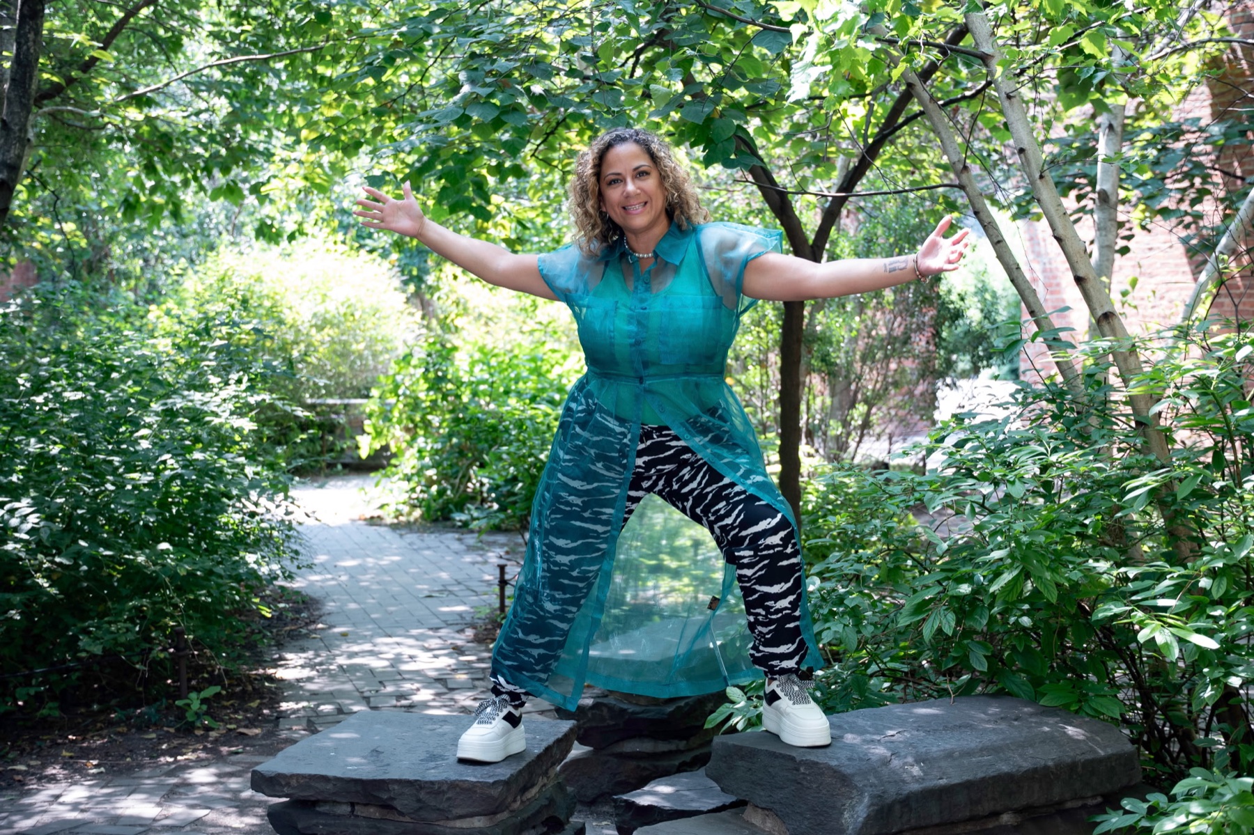Ivelisse Gutierrez standing with her arms open in a garden.